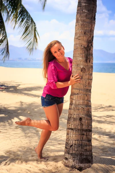 Meisje in roze tegen zand en zee — Stockfoto