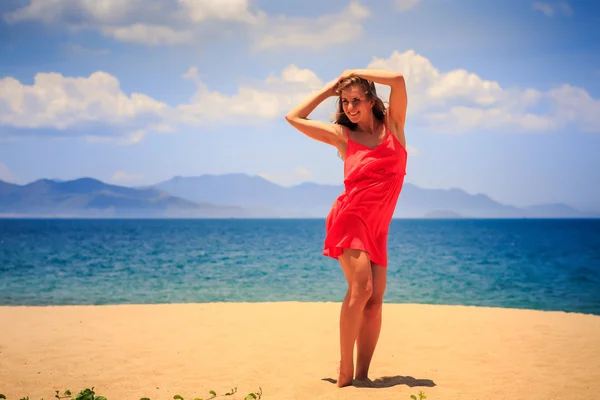 Blond girl in red   on sand beach — Stok fotoğraf