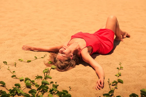 Blond girl in red   on sand beach — Stok fotoğraf