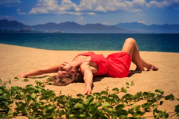 Blond girl in red   on sand beach — Stok fotoğraf