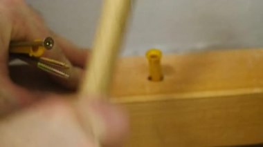 Çekiçle insan eli vuruşları plastik duvar demirini ahşap kaplamalara monte ediyor. İşçi ustalıkla duvar montajı için gerekli aracı ekler