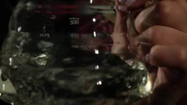 İşçi, ağır çekim için kahve yapmadan önce konteynırı duruluyor. Barista az miktarda suyla dolu cam sürahiyi sallıyor..