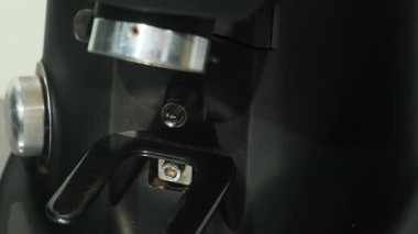 Barista dikkatlice endüstriyel kahve makinesine metal iskele filtresi yerleştiriyor. Çalışanların kahve hazırlama işlemleri yavaş çekimde.