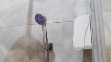 Temiz banyodaki parlak fayanslı duvara krom duş başlığı ve musluk karıştırıcısı. Otel odasında su ile yıkanan vücut için modern ekipman.