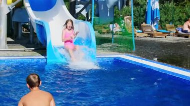 Küçük kız, Aquapark ağır çekimde havuza doğru kayarken çığlıklar atıyor. Çocuklar havuz başında yüzer ve gezintiye çıkar. Yaz tatili