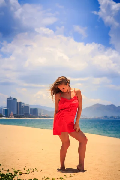 Menina loira em vermelho fica na praia — Fotografia de Stock