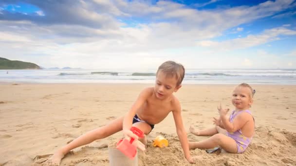 Zwei Kinder spielen am Strand — Stockvideo