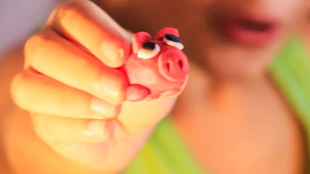 Дівчина показує пластилінову свиню — стокове відео
