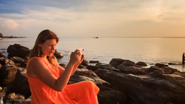 Woman taking picture of sunset coast — Stock Video