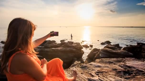 Mulher tirando fotos da costa do pôr do sol — Vídeo de Stock