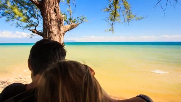 Chico y chica sentarse contra el cielo azul — Vídeos de Stock