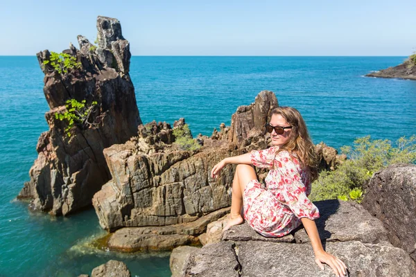 Женщина, сидящая на прибрежных скалах — стоковое фото