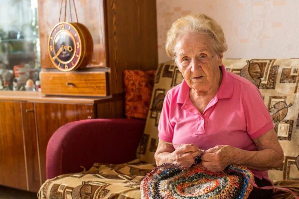 Frau sitzt und strickt Teppich. — Stockfoto