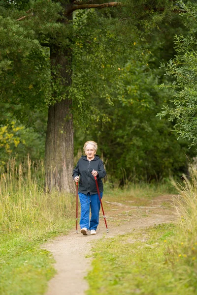 Woman is engaged in Nordic walking — Stockfoto