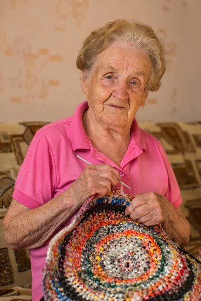 Woman sits knitting a rug. — Stock Photo, Image