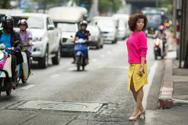 Jovem mulher asiática fica perto de uma cidade movimentada rodovia . — Fotografia de Stock