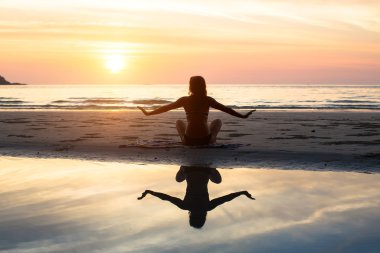 Muhteşem gün batımı ve deniz arka plan üzerine siluet yoga kadın. Sağlıklı yaşam tarzı.
