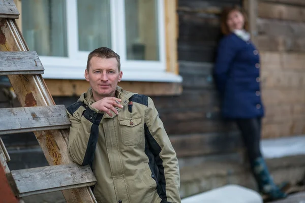 Ung man röka en cigarett stående nära gården. — Stockfoto