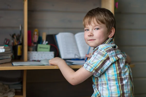 Junge sitzt am Tisch und macht Hausaufgaben. — Stockfoto