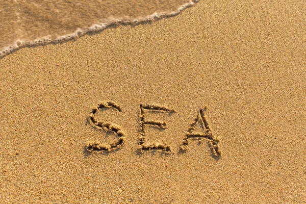 Море - написано на песчаном пляже — стоковое фото