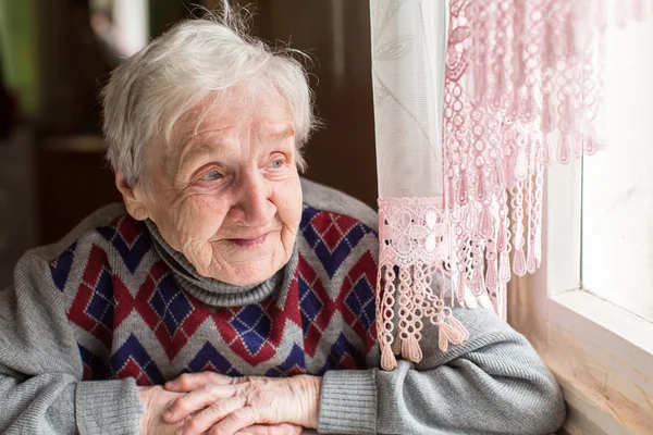 Babcia patrząc przez okno — Zdjęcie stockowe