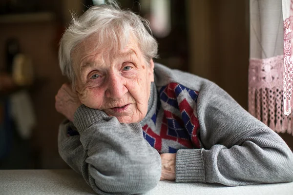 Elderly woman near the window — Stock Photo, Image