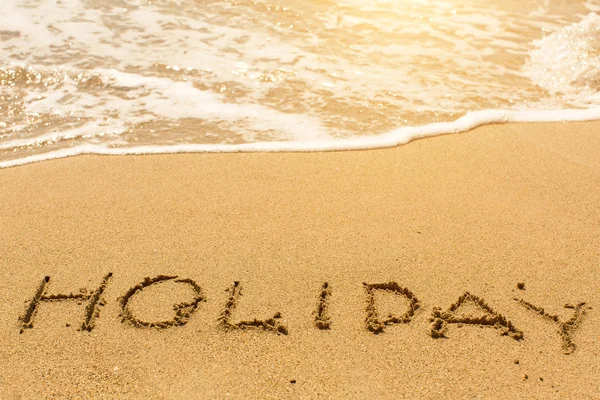 Holiday - written on sandy beach Royalty Free Stock Images