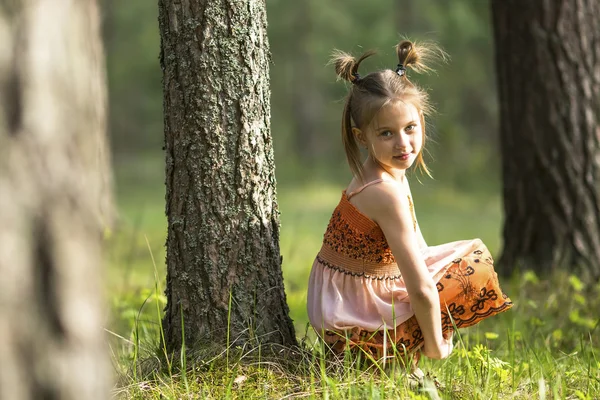 Liten flicka sitter nära ett träd — Stockfoto