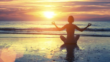 Kadın plajda yoga yapıyor.