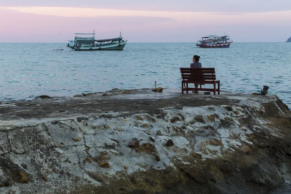 Жінка сидить на лавці біля моря — стокове фото