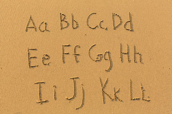 Letras do alfabeto desenhadas na praia — Fotografia de Stock