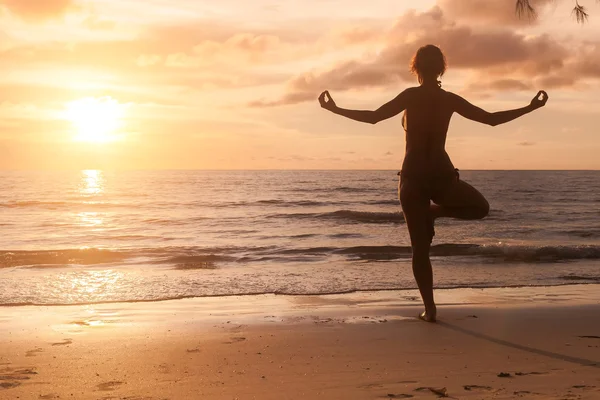 Flicka som utövar yoga vid havets strand — Stockfoto