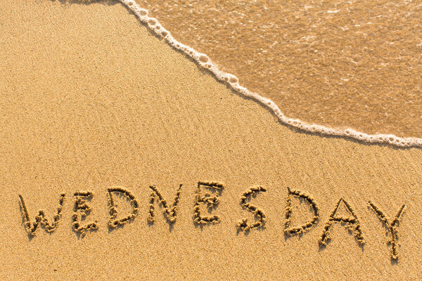 Wednesday inscription on sandy beach
