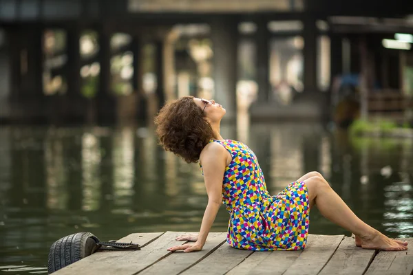 Kız bir nehir rıhtım üzerinde oturuyor. — Stok fotoğraf