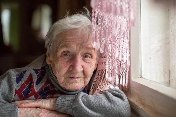 Oudere vrouw siiting aan de tafel — Stockfoto