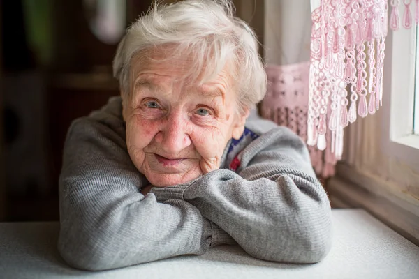 Mulher idosa siiting na mesa — Fotografia de Stock