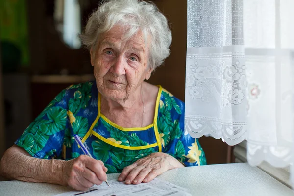 Emekli kadın faturalar doldurur — Stok fotoğraf