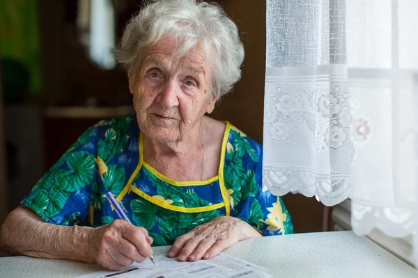 Gepensioneerde vrouw invult nutsrekeningen — Stockfoto