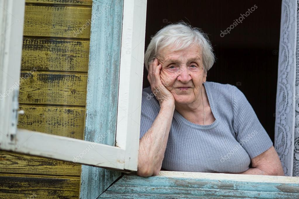 Rentnerin schaut aus dem Fenster Stockfotografie