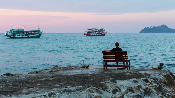 man sitting on sea pier
