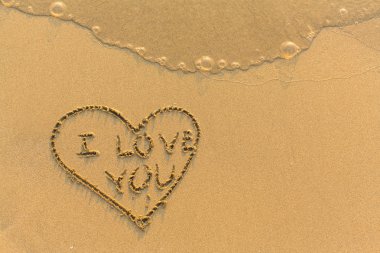 Kalp ve ı Love You kum üzerinde.