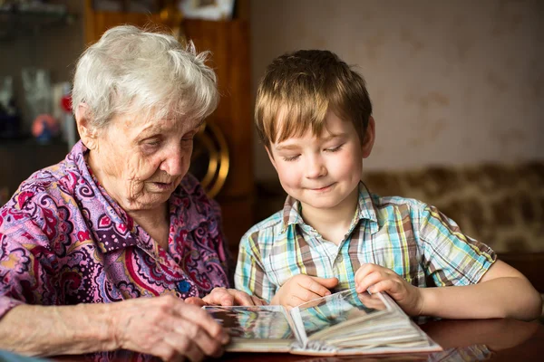 Elderly woman with grandson looking album — Stock Photo, Image