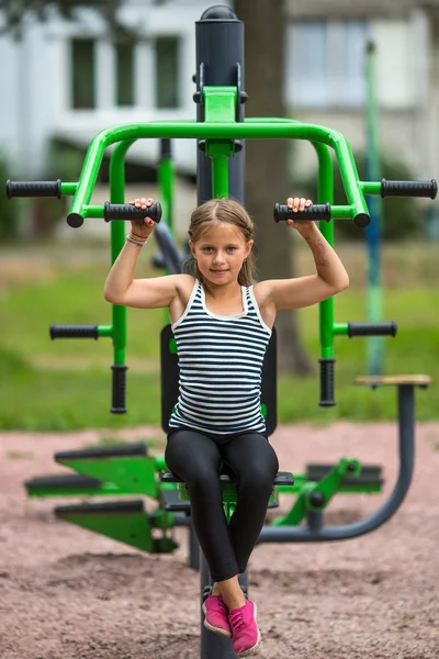 Meisje zittend op fitnessapparatuur — Stockfoto