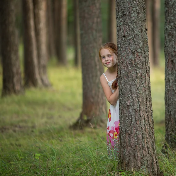Menina espreitando de trás de uma árvore — Fotografia de Stock