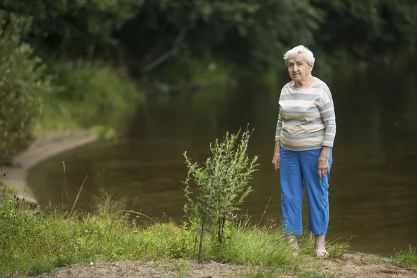 Kobieta stoi na brzegu jeziora — Zdjęcie stockowe