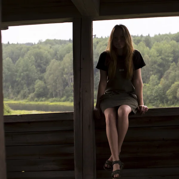 Dívka sedí na zábradlí dřevěné altány — Stock fotografie