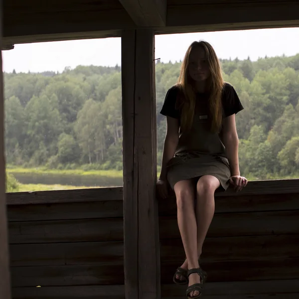 Ragazza seduta sulla ringhiera di un gazebo di legno — Foto Stock