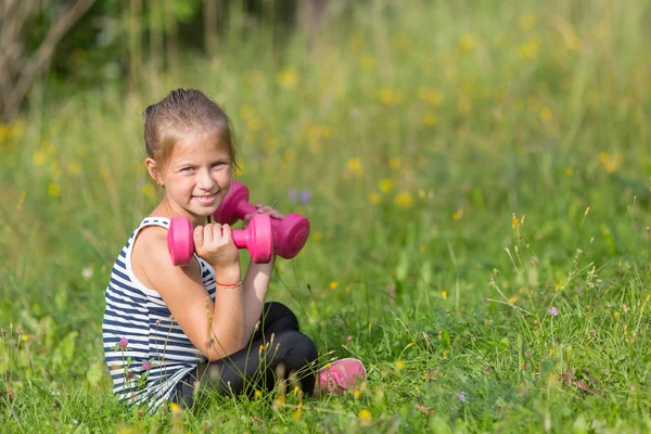 Маленька дівчинка з гантелями — стокове фото