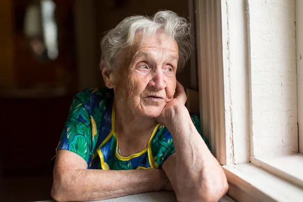 La abuela mira por la ventana — Foto de Stock