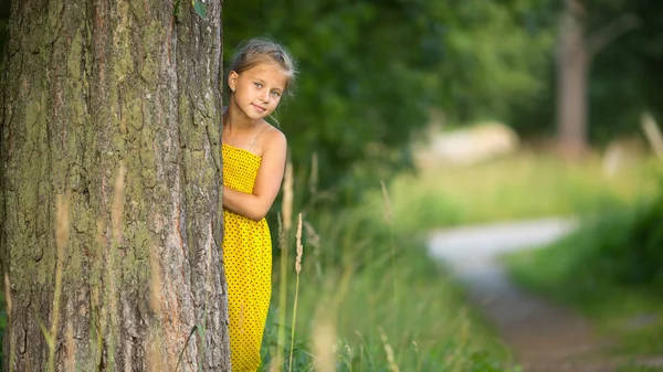 Lilla flickan bakom träd — Stockfoto